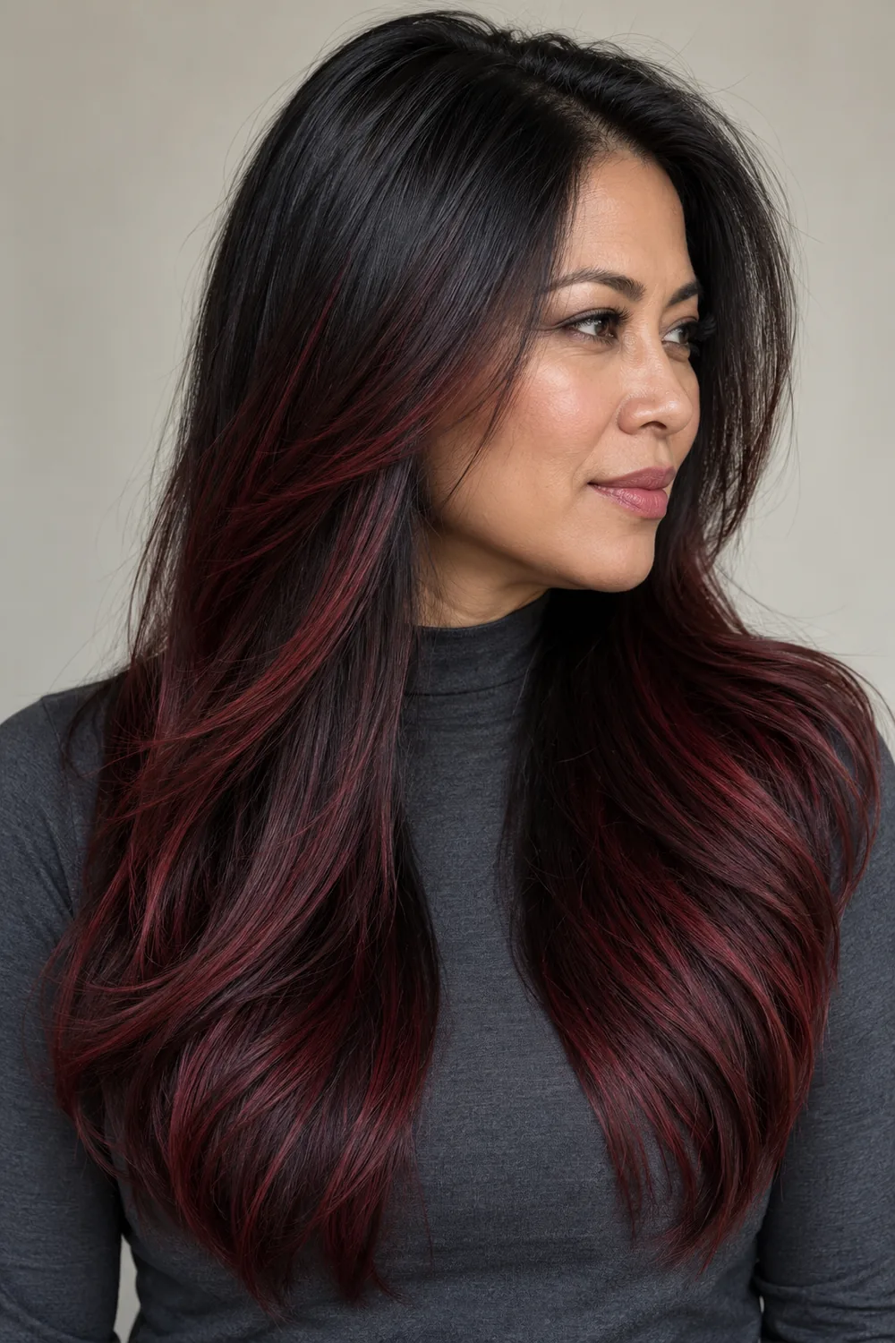 A fictional adult woman in three-quarter profile with long straight black hair, a dark shadow root, and burgundy ribbons through the lengths.