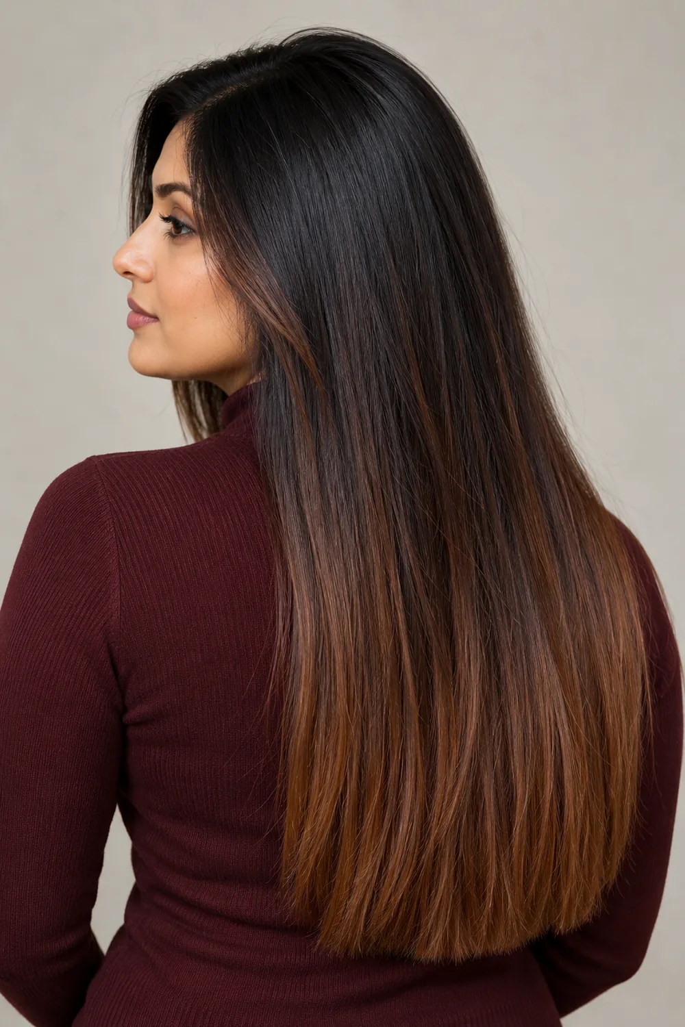 A woman in a burgundy top with long, sleek near-black brunette hair that gradually warms to cinnamon brown auburn ends.