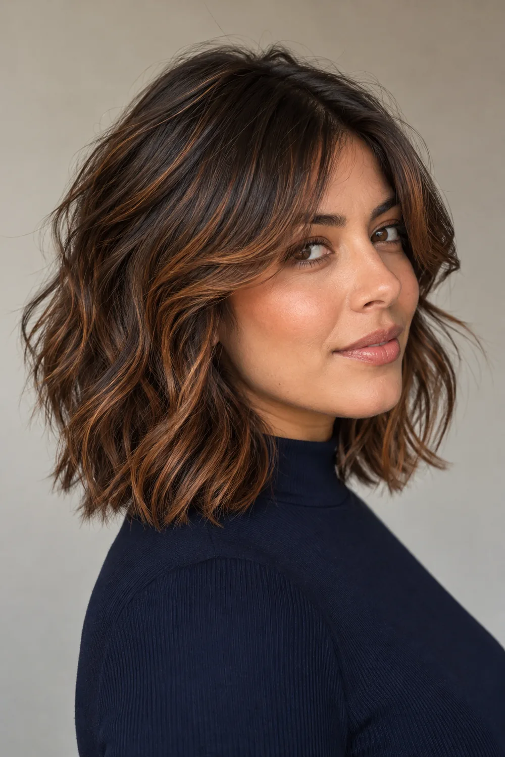 Adult woman with a collarbone-length dark brown shag, curtain fringe, and copper ribbons woven through the waves and ends.