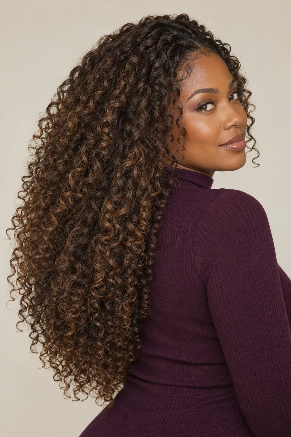 Long natural curls in mocha brown with warm ribbon highlights along the outer layers, shown over one shoulder.